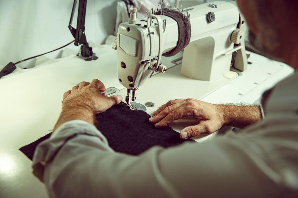 A tailor adjusting the waist of a pair of pants.
